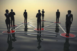 A business network of successful executives in silhouettes at sunset on an ocean.
